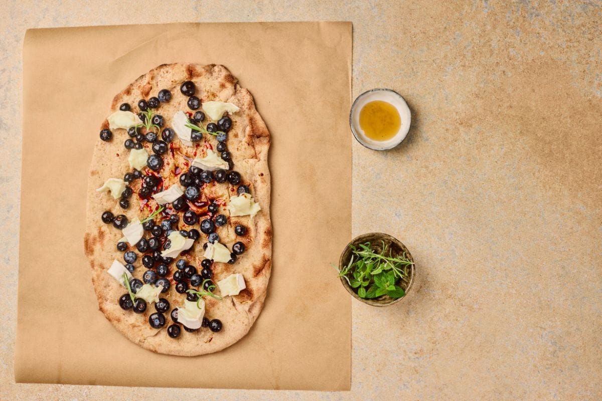 Pizza with blueberries, mozzarella, herbs, and olive oil.