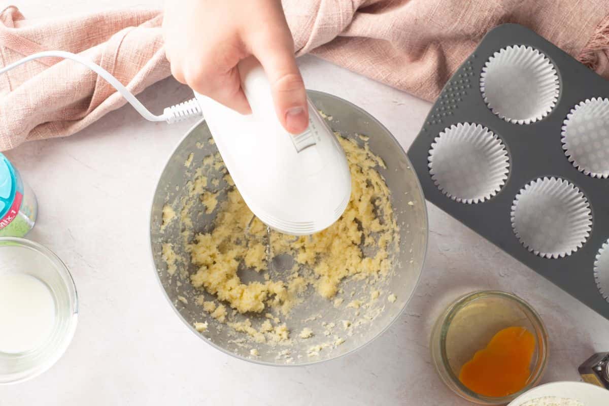 Hand mixing cookie dough with an electric beaters in a kitchen.