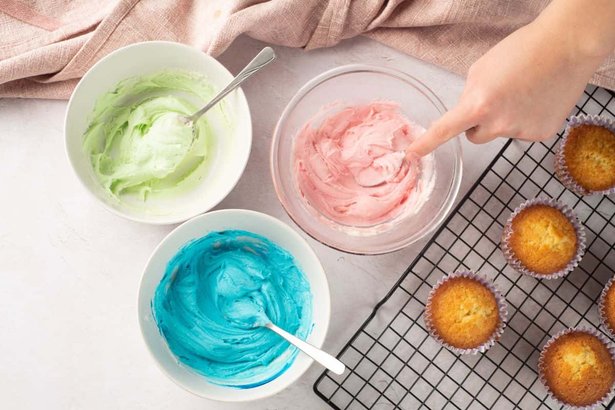 Bright cupcakes topped with vibrant pastel frosting in pink, green, and blue for a fun baking session.