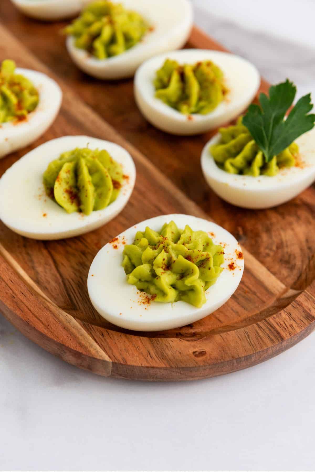Creamy deviled eggs topped with avocado and paprika, perfect for Easter snacking.