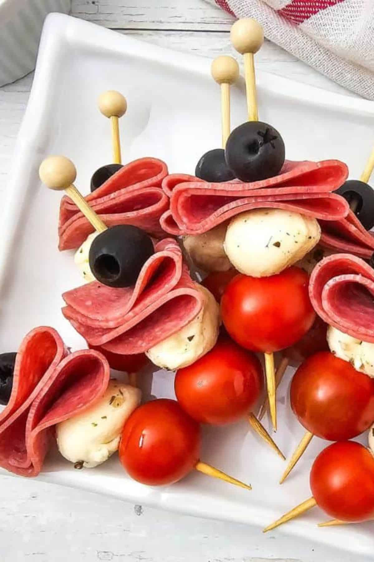 Fresh take on easy Easter appetizers with cherry tomatoes, mozzarella, ham, and black olives on skewers.