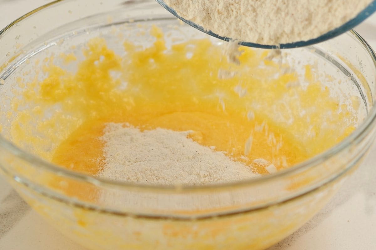 Close-up of baking ingredients being mixed in a glass bowl, including eggs and flour, for a homemade recipe.