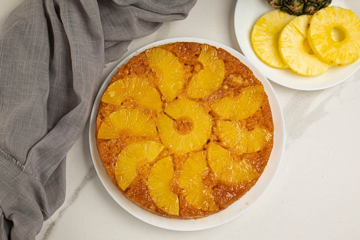 Bright pineapple slices on a golden cake with fresh fruit on the side. Perfect for summer desserts.